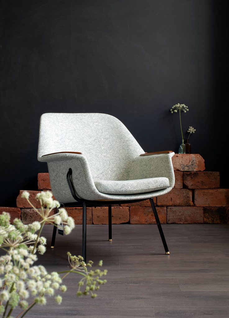 Kunnostettu Havui-nojatuoli 50-luvulta (jalat: putkirunko, istuinrunko taivutettua vaneria), kankaana: Ruska-kuosi väreissä pullonvihreä/valkoinen. Tuoli kuvattuna etuviistosta.