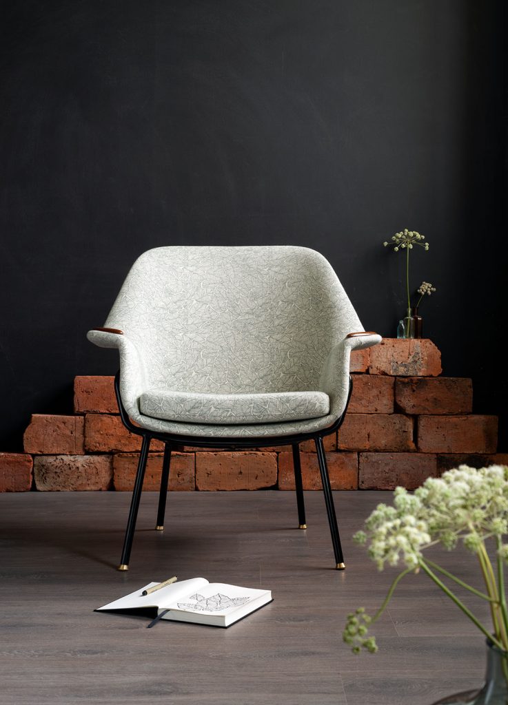 Kunnostettu Havui-nojatuoli 50-luvulta (jalat: putkirunko, istuinrunko taivutettua vaneria), kankaana: Ruska-kuosi väreissä pullonvihreä/valkoinen. Tuoli kuvattuna edestäpäin.