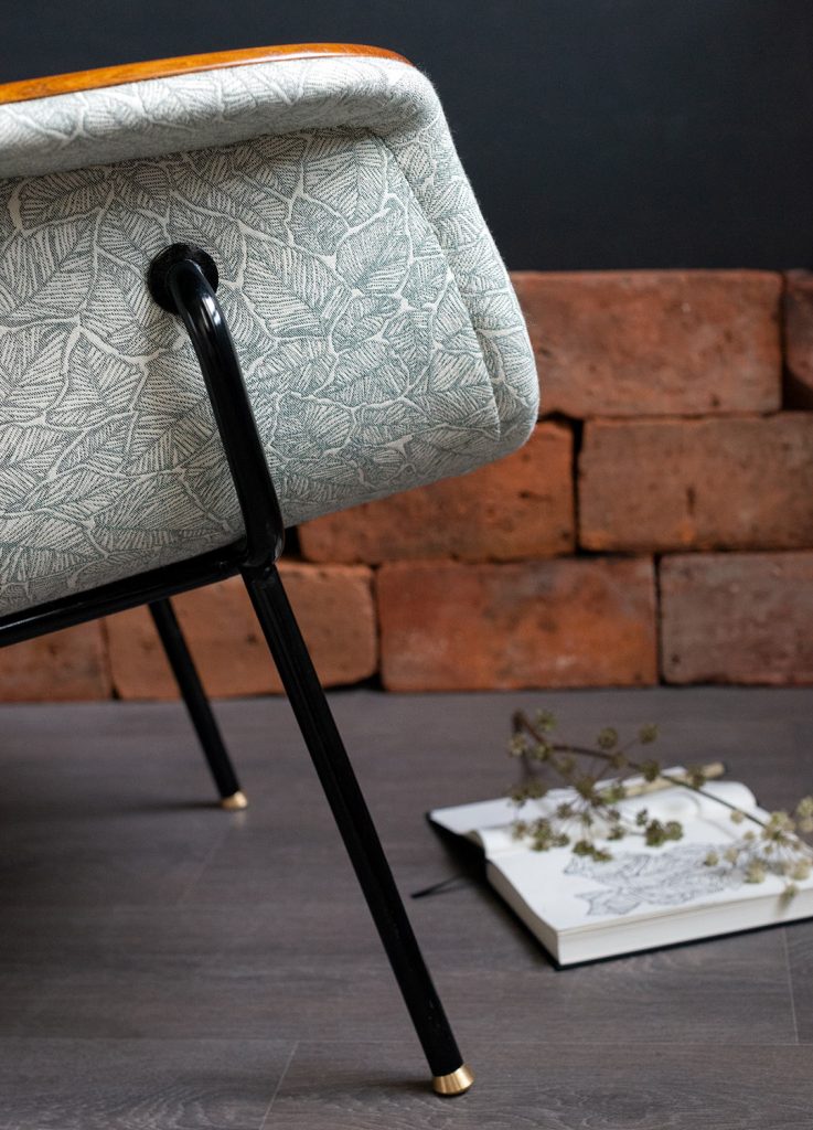 Kunnostettu Havui-nojatuoli 50-luvulta (jalat: putkirunko, istuinrunko taivutettua vaneria), kankaana: Ruska-kuosi väreissä pullonvihreä/valkoinen. Yksityiskohta sivulta.